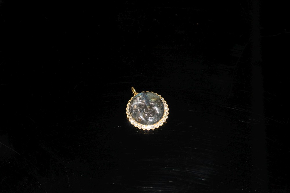 A 20th century yellow metal, diamond and carved labradorite? moon face pendant, 26mm, gross weight 7.2 grams.